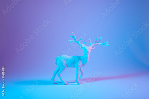 Christmas background with white decorative deer on blue holographic background. Banner format  copy space.