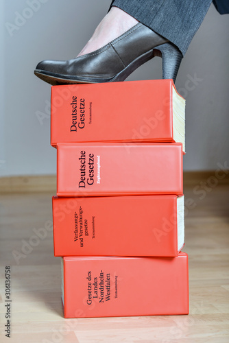 Konzept: „Entschlossene, starke Anwältin“ Streitlustige Anwältin mit einem Schuh auf vier Gesetzbüchern.