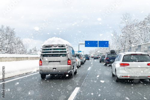 Winter highway with many different cars stucked in traffic jam due ti bad weather conditions. Vehicles on road during heavy snowstorm and blizzard on cold winter day in Austria near Germany border