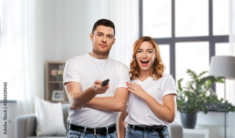 entertainment, television and people concept - couple in white t-shirts with tv remote control over grey background entertainment, television and people concept - couple in white t-shirts with tv remote control over grey background