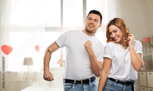 valentine's day, relationships and people concept - happy couple in white t-shirts dancing over bedroom decorated with heart shaped balloons background