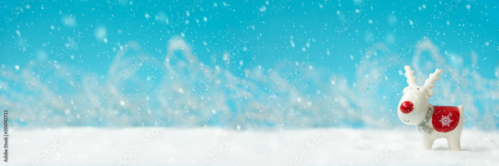 Banner 3:1. Ceramic Christmas reindeer toy on snowy background. Christmas or New Year celebration concept. Copy space Banner 3:1. Ceramic Christmas reindeer toy on snowy background. Christmas or New Year celebration concept. Copy space