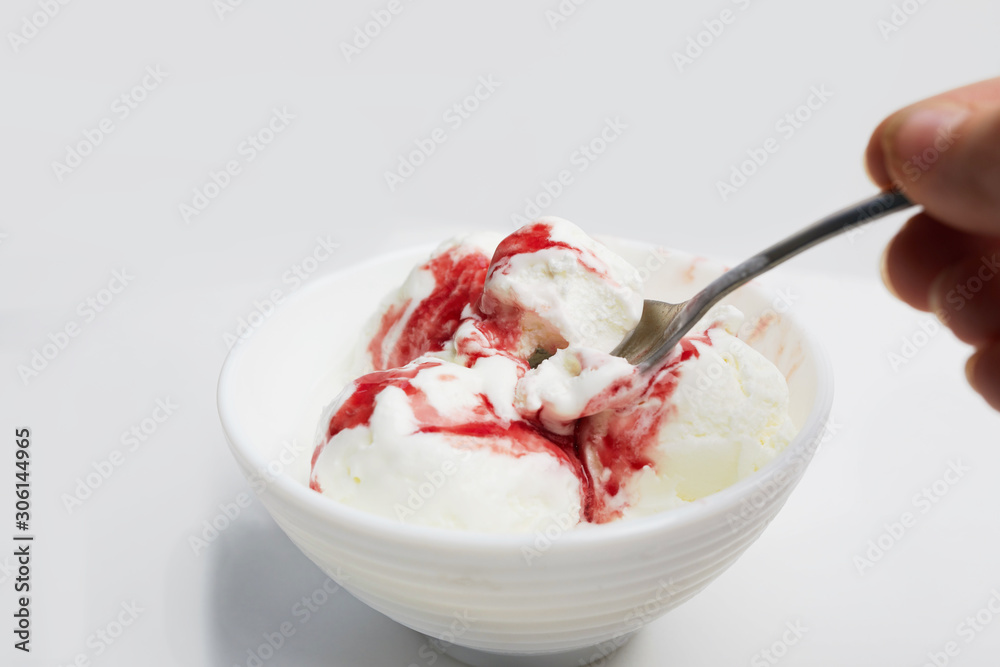 hand with spoon takes ice cream from bowl. balls of white ice cream with red berry syrup on white background hand with spoon takes ice cream from bowl. balls of white ice cream with red berry syrup on white background