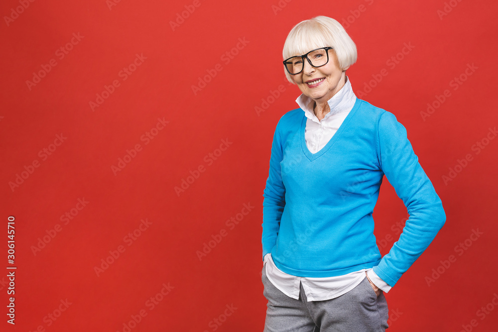Senior happy aged businesswoman wearing glasses. Beautiful old woman looking at camera and smiling. Isolated on red background.