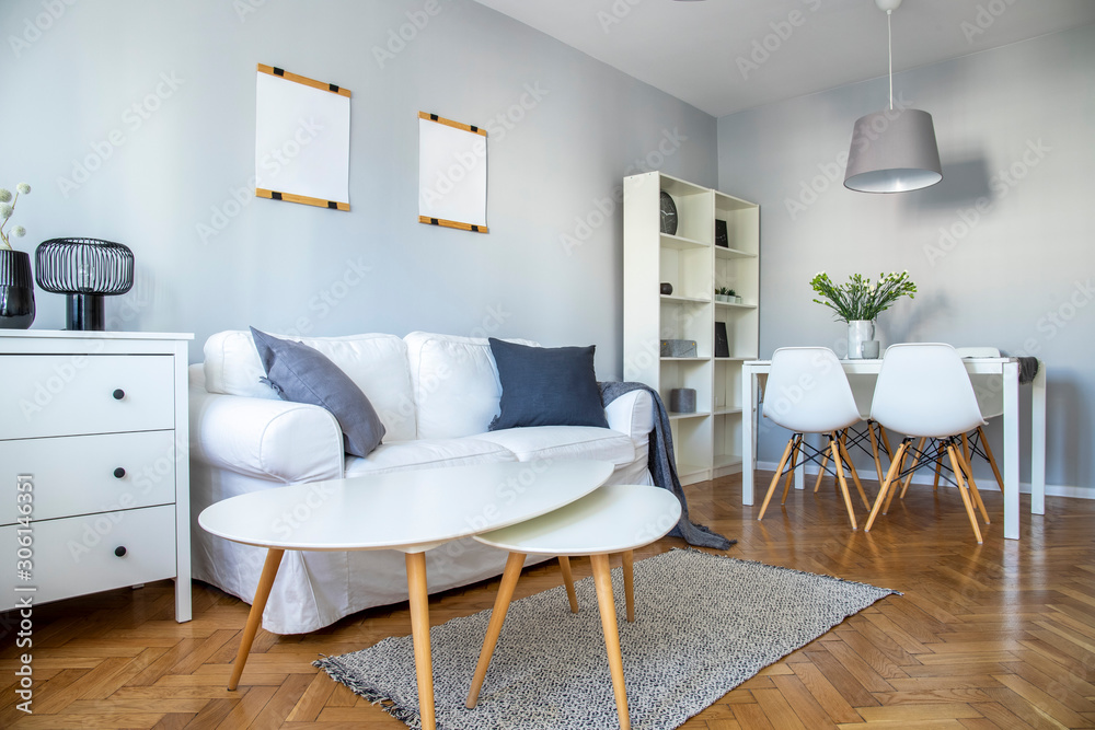 Fototapeta premium Stylish coffee table, comfortable sofa and dining room furniture in grey room