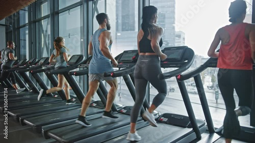 Group of Six Athletic People Running on Treadmills, Doing Fitness Exercise. Athletic People Actively Workout in the Modern Gym. Sports People Workout in Fitness Club. Side View Slow Motion