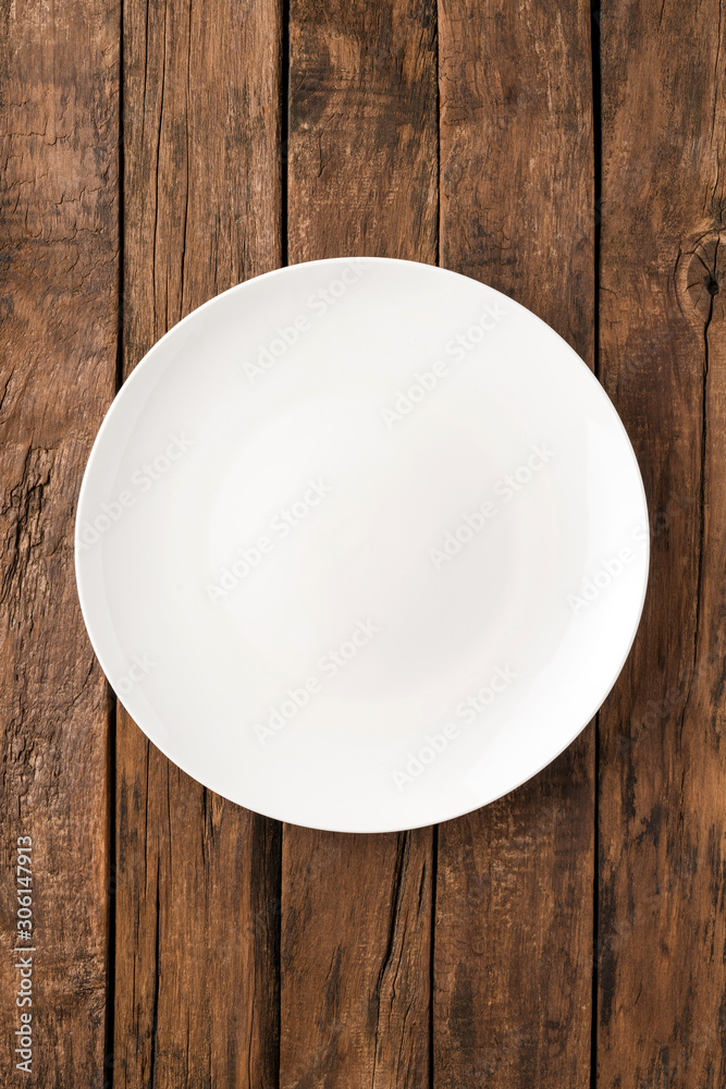 Overhead shot of blank white dish on rustic wooden table. Close up Overhead shot of blank white dish on rustic wooden table. Close up