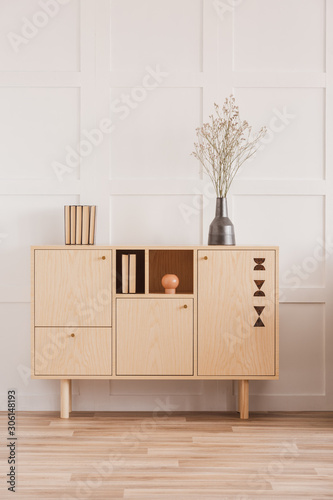 Dry flowers in vase on wooden commode in classy daily room