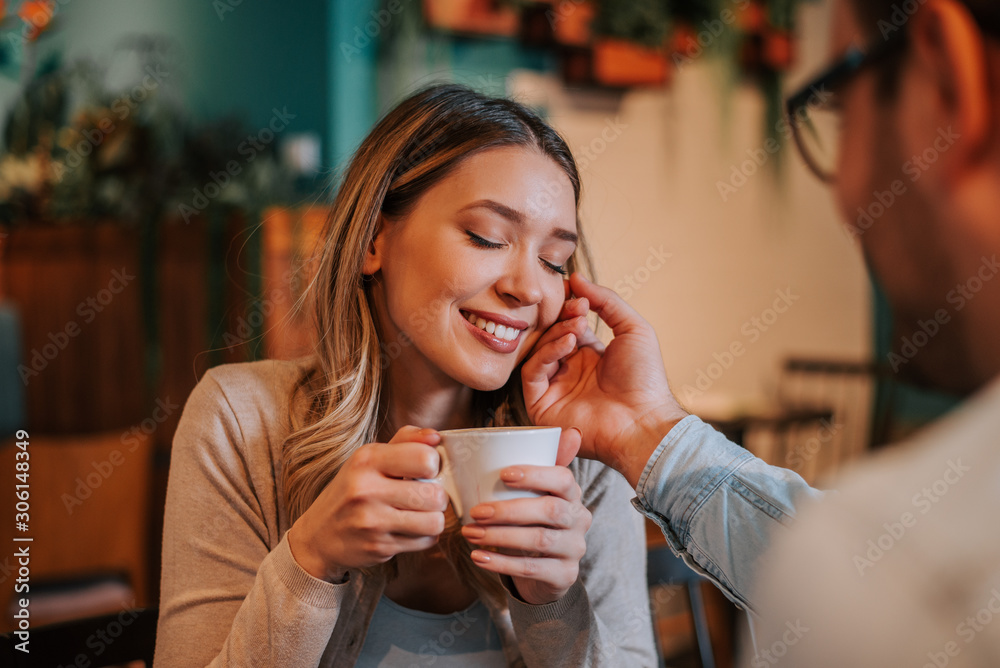 Loving couple in the cafe. Man caressing woman's face.