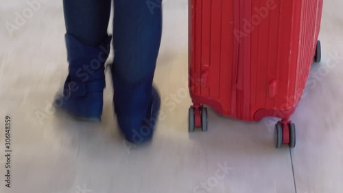 Blue boots and wheel red luggage whic woman holding hand walking  in the Airport photo