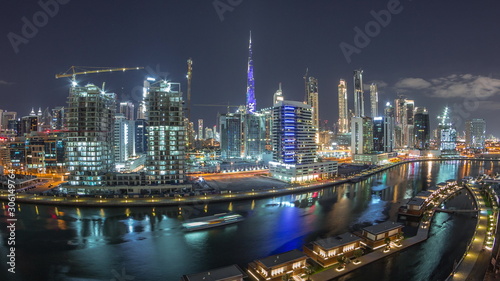 Night city Dubai near canal with bright skyscrapers aerial timelapse