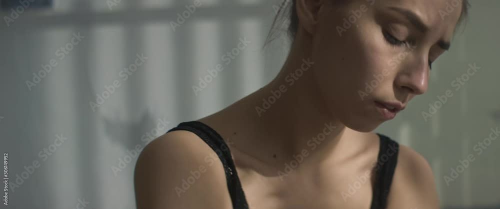 Young beautiful Caucasian girl in black T-shirt crying at home in large bright room. Feeling alone and depressed. Sadness, bad mood, tears, unhappiness. Anamorphic lens, handheld shot Young beautiful Caucasian girl in black T-shirt crying at home in large bright room. Feeling alone and depressed. Sadness, bad mood, tears, unhappiness. Anamorphic lens, handheld shot