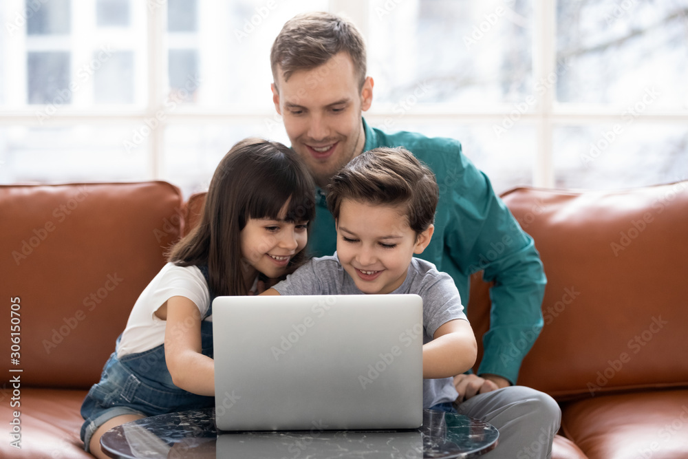 Happy father have fun using laptop with little kids Happy father have fun using laptop with little kids