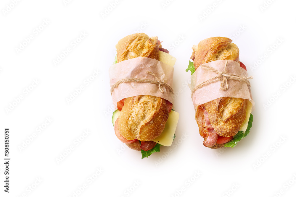Two fresh big baguette sandwiches with bacon, chedder cheese, mustard, lettuce and vegetables isolated on white background Two fresh big baguette sandwiches with bacon, chedder cheese, mustard, lettuce and vegetables isolated on white background