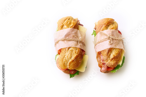 Two fresh big baguette sandwiches with bacon, chedder cheese, mustard, lettuce and vegetables isolated on white background