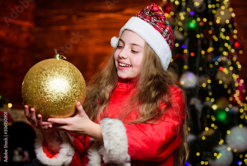 Happy new year. Elf child with decorative ball. Xmas tree. Happy holiday. Little girl in red hat. Happy christmas. Santa claus little girl. Chriatmas interior. Christmas time. Express positivity photo