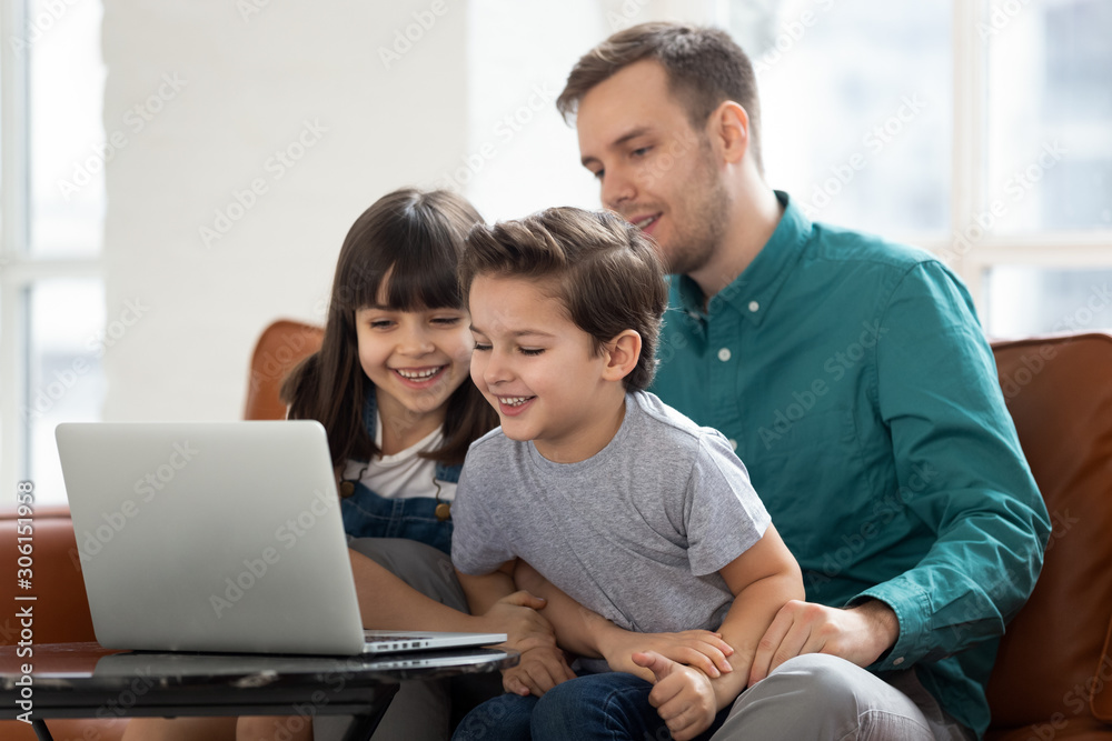 Happy little kids play on laptop relaxing with dad Happy little kids play on laptop relaxing with dad