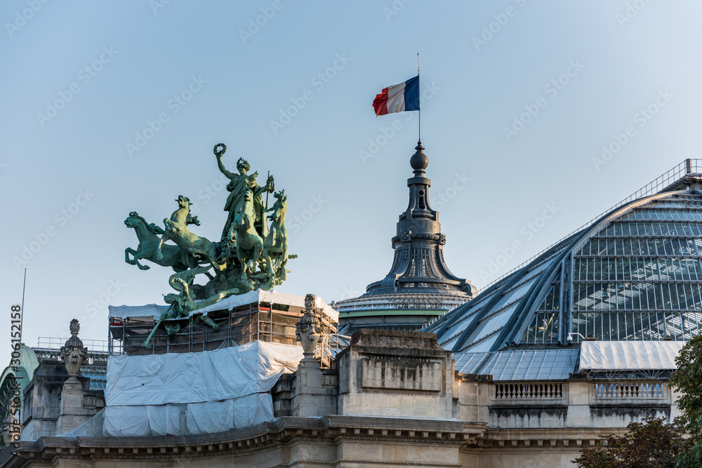 French National Flag  and statue on The Grand Palais in Paris, currently the largest existing ironwork and glass structure in the world