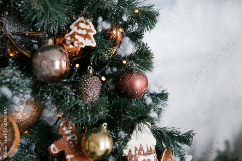Golden Christmas decorations with citruses, gingerbread cookies and cinnamon on a Christmas tree in the home interior