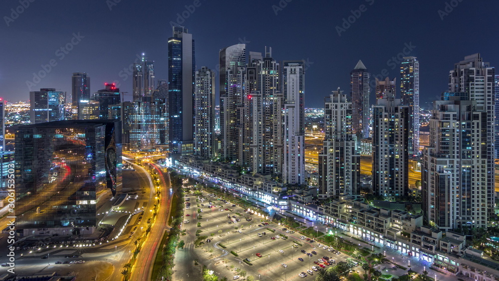 Modern residential and office complex with many towers aerial night timelapse at Business Bay, Dubai, UAE.