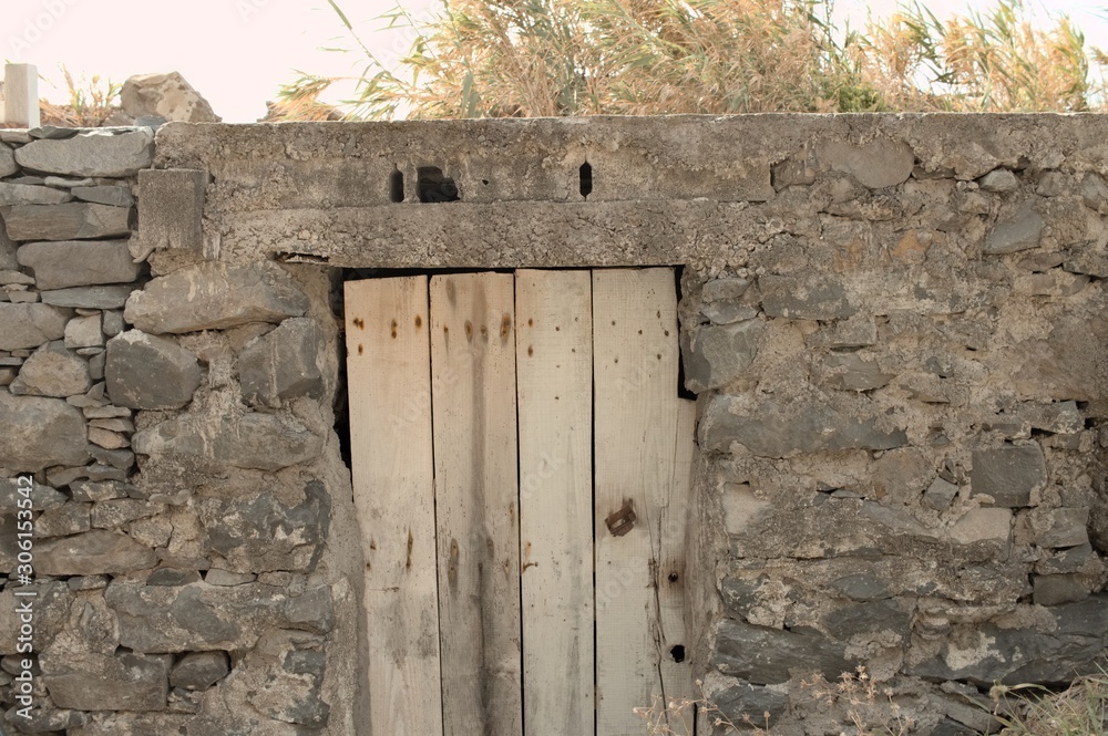 Isolated old wooden door in a stoned wall of a rural place (Madeira, Portugal, Europe) Isolated old wooden door in a stoned wall of a rural place (Madeira, Portugal, Europe)