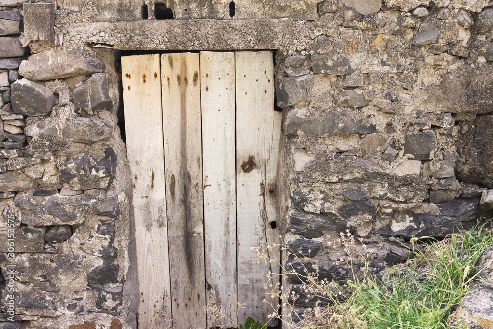 Isolated old wooden door in a stoned wall of a rural place (Madeira, Portugal, Europe) Isolated old wooden door in a stoned wall of a rural place (Madeira, Portugal, Europe)