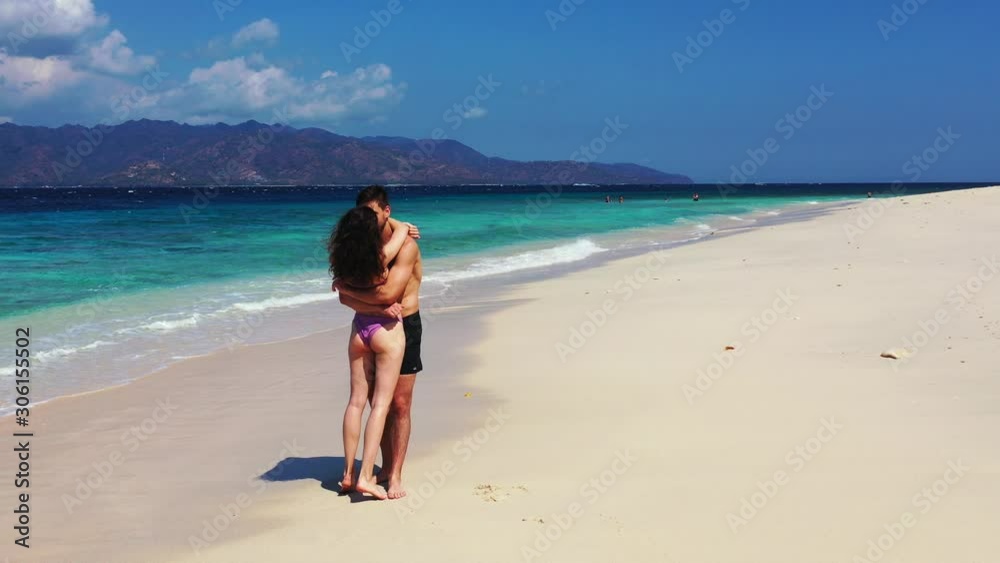 Carribean Island Resort Showing Gorgeous Couple Embracing Each Other By The Shore With Scenic Attractions Behind Them - Wide Shot Carribean Island Resort Showing Gorgeous Couple Embracing Each Other By The Shore With Scenic Attractions Behind Them - Wide Shot