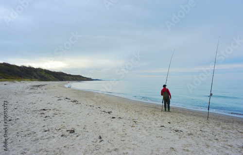Fototapeta Naklejka Na Ścianę i Meble -  A person is fishing on the baltic sea shore on the Darsß peninsula in Germany