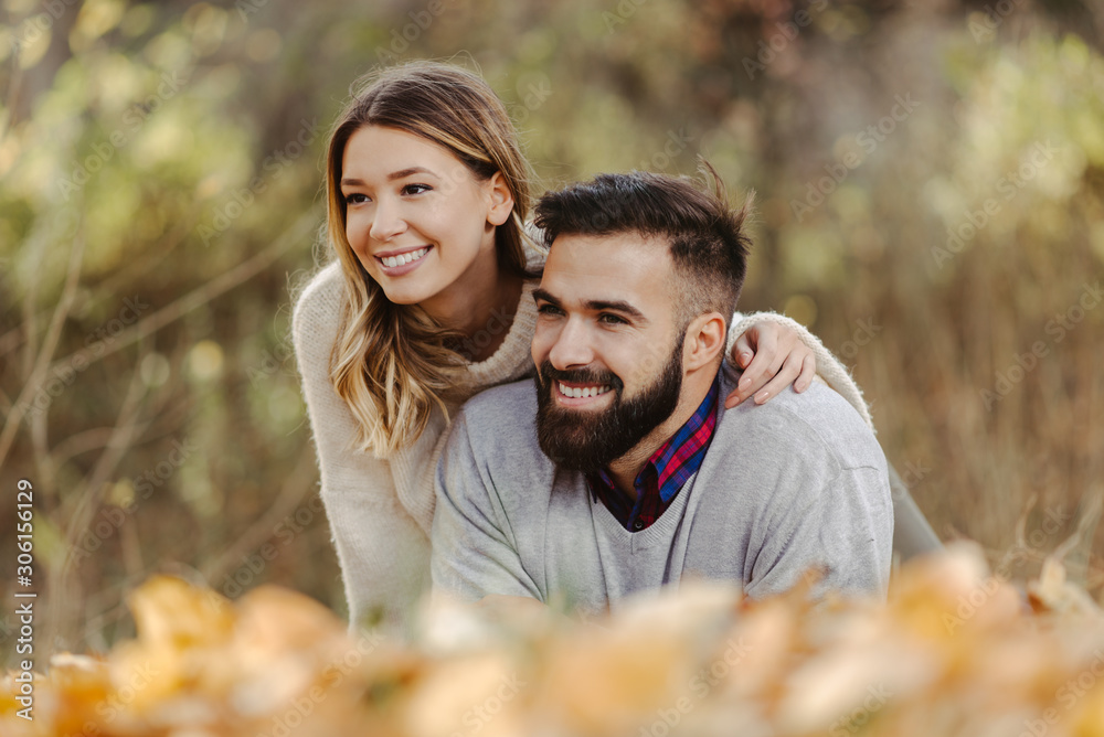 Smiling couple relaxing together outdoors and enjoying in autumn day. Woman is in focus Smiling couple relaxing together outdoors and enjoying in autumn day. Woman is in focus