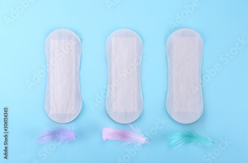 Menstrual pad with feathers on color background 