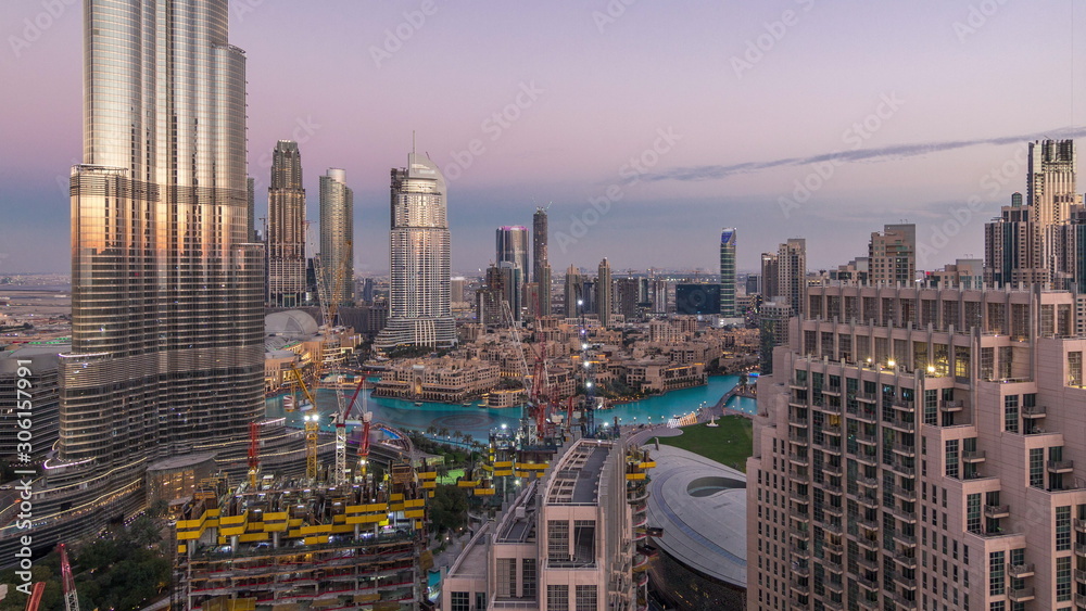 Fototapeta premium Panoramic skyline view of Dubai downtown after sunset with mall, fountains and skyscrapers aerial day to night timelapse