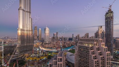 Panoramic skyline view of Dubai downtown after sunset with mall, fountains and skyscrapers aerial day to night timelapse