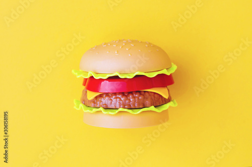 Toy burger with meat and salad on an yellow background. photo