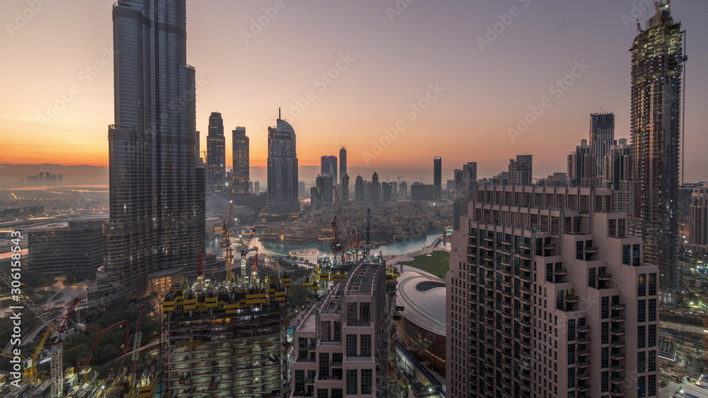 Panoramic skyline view of Dubai downtown before sunrise with mall, fountains and skyscrapers aerial night to day timelapse