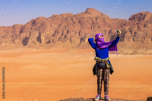 Wallpaper Mural Caucasian travel girl with Eastern traditional hijab making selfie staying on edge of high cliff with unfocused background of desert valley and sand stone mountain ridge Middle East scenic view  Torontodigital.ca