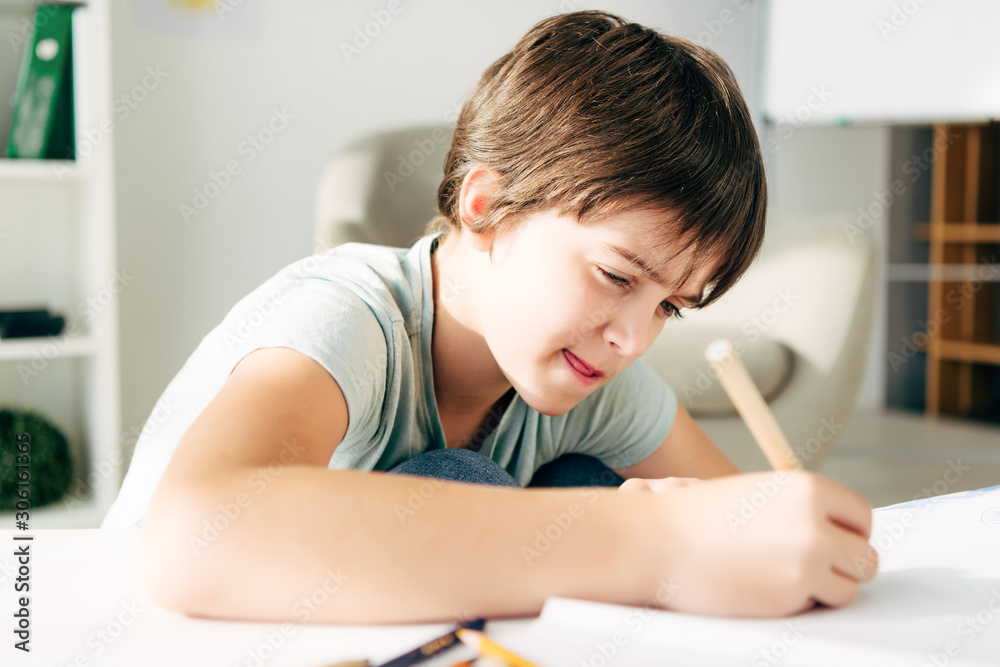 kid with dyslexia drawing with pencil and sitting at table kid with dyslexia drawing with pencil and sitting at table