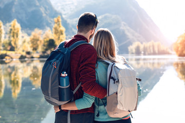 Two travel hikers in love enjoying the nature while looking the landscape in front of the lake in mountain.