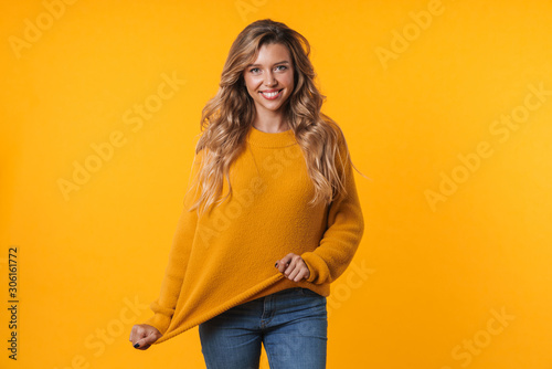 Image of happy blonde woman wearing warm sweater smiling at camera