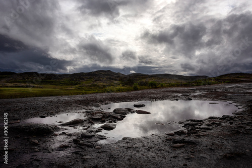 Russia, Arctic, Kola Peninsula, Barents Sea, Teriberka: Rural remote natural place with rocky wildness, dark grey gloomy cloudy sky and calm puddle water - concept outdoor adventure recreation nature