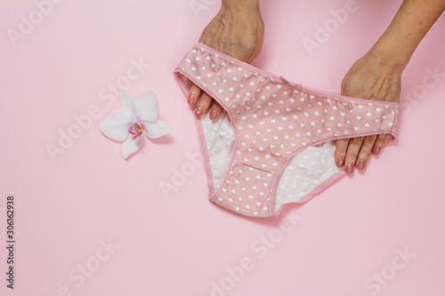Women's hands with beautiful panties on pink background.