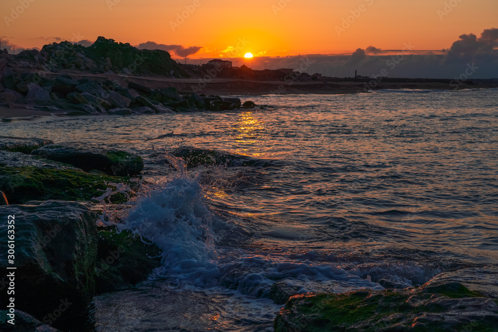 Splashing waves on the coastal cliffs at sunset