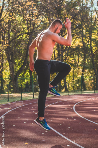 Male model with muscular fit and slim body at the city stadium. 