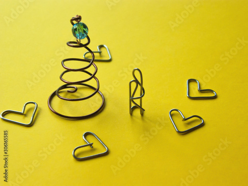 lovers at the Christmas tree .installation of paper clips on a yellow background