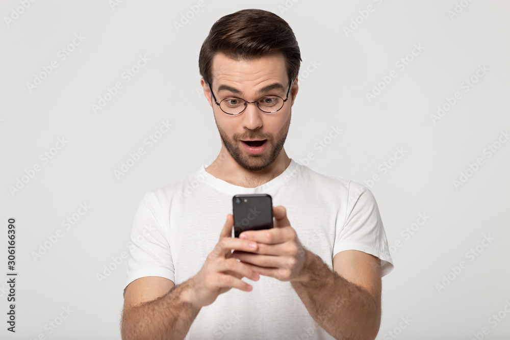 Caucasian man in glasses surprised by message on cellphone Caucasian man in glasses surprised by message on cellphone