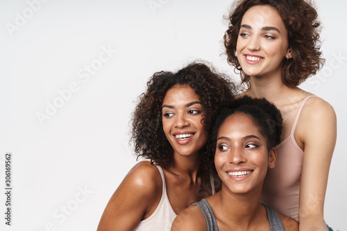 Portrait of three cheerful multiracial women smiling and looking aside