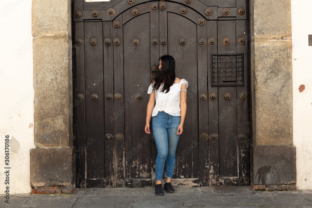 Hispanic tourist turning to see in colonial city - Antigua Guatemala - ancient door