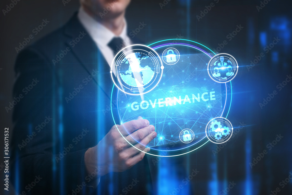 Business, Technology, Internet and network concept. Young businessman working on a virtual screen of the future and sees the inscription: Governance Business, Technology, Internet and network concept. Young businessman working on a virtual screen of the future and sees the inscription: Governance