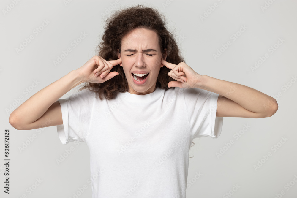 Stressed millennial girl cover ears avoiding noise Stressed millennial girl cover ears avoiding noise