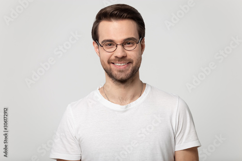 Headshot portrait of smiling man in glasses on studio background