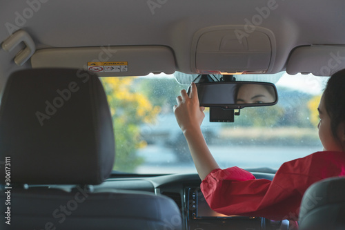 Portrait of woman in the car adjusts the rear view mirror before travel. Safety concept.